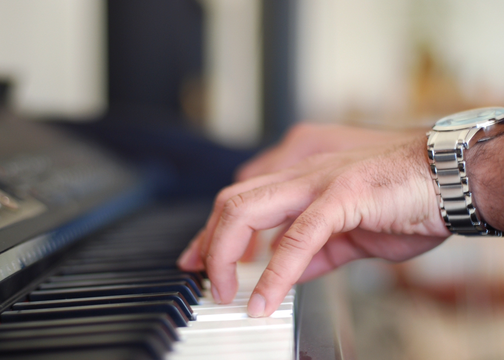 Hand playing piano keys in soft focus